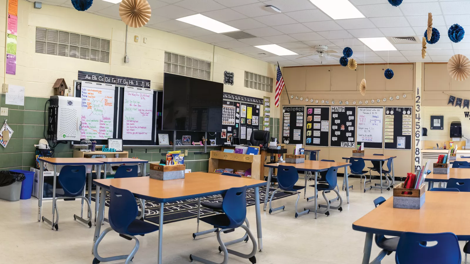 panoramic photo of school classroom with white board, desks, and sign by the door that says You Matter