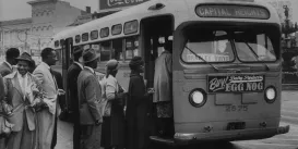A black and white historic image of people filing into a bus from the Montgomery Bus Boycott.
