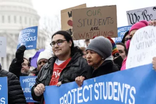 A crowd of people holding various signs about supporting public education.