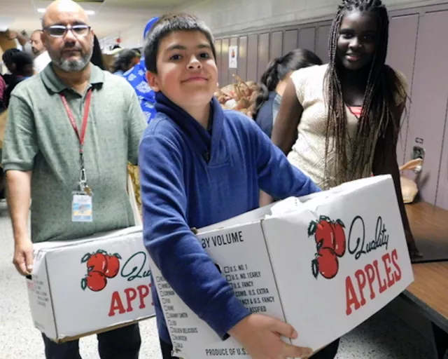 students and staff distribute food at a community school